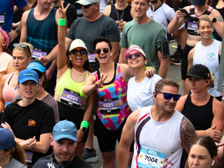 People waving and smiling at the start line of a running race