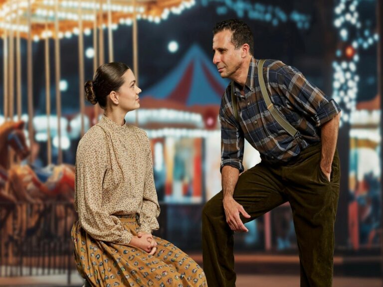 woman and man looking at each other with a carousel behind them