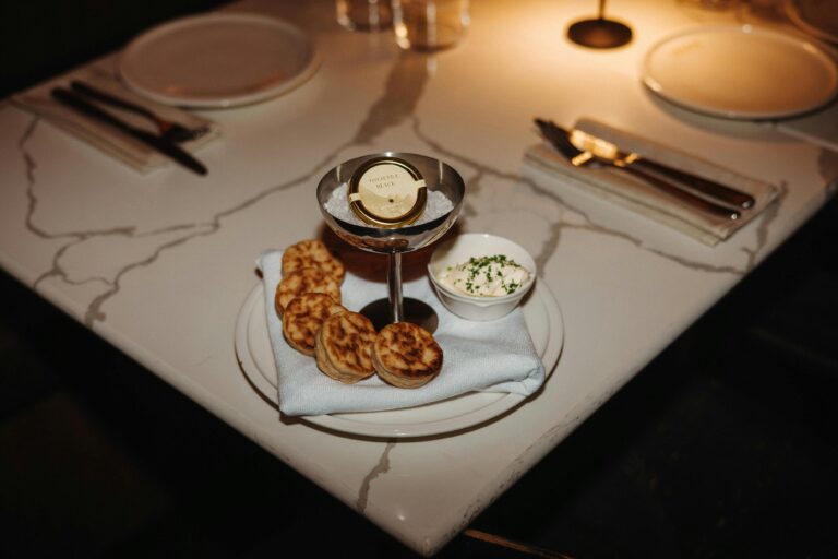 Caviar in a silver cup on a plate with small crumpets on it