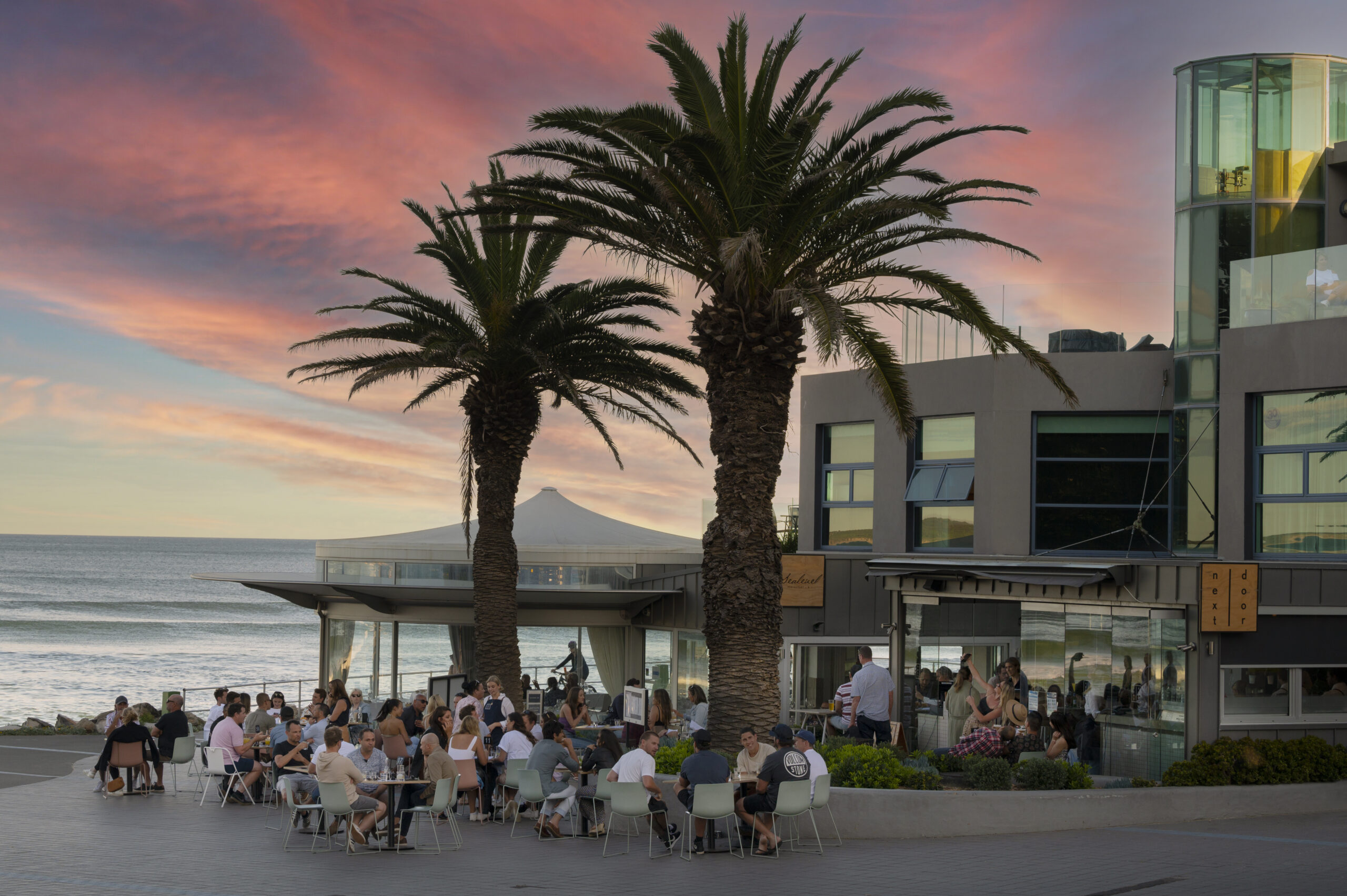 Patrons dining outdoors at dusk outside of Next Door cafe