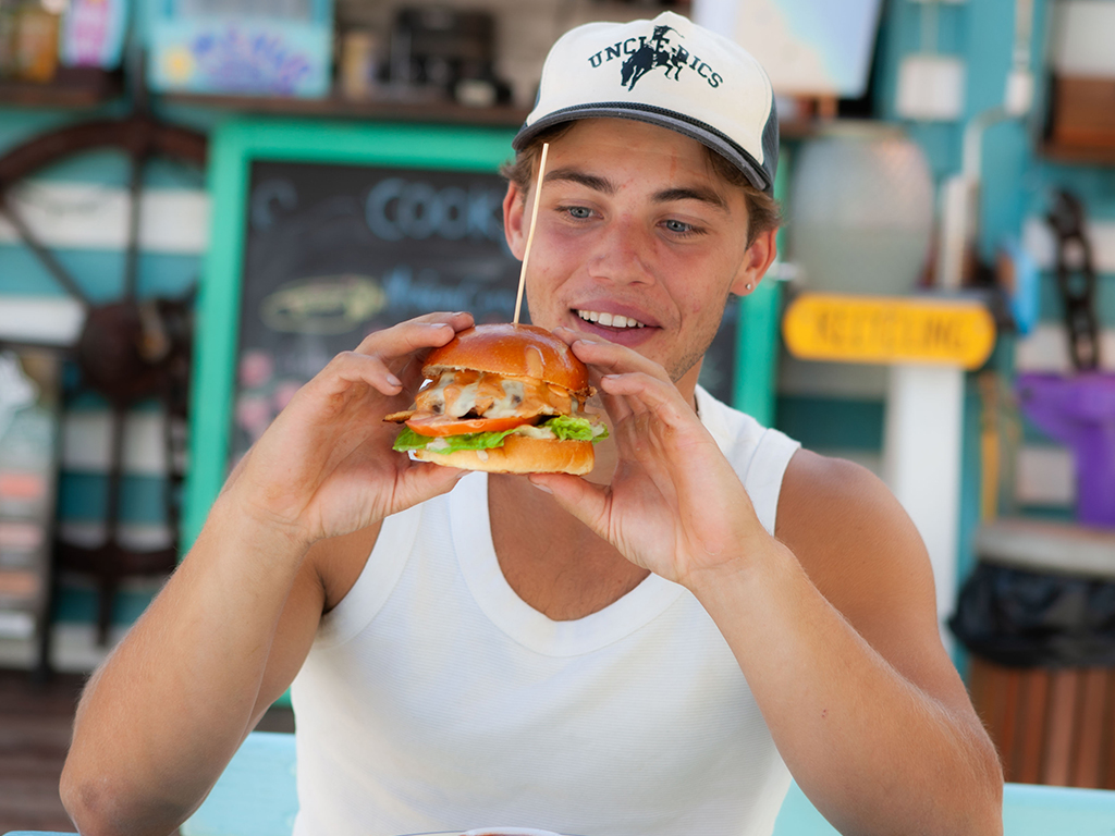 Man holding a hamburger outdoors at Cook