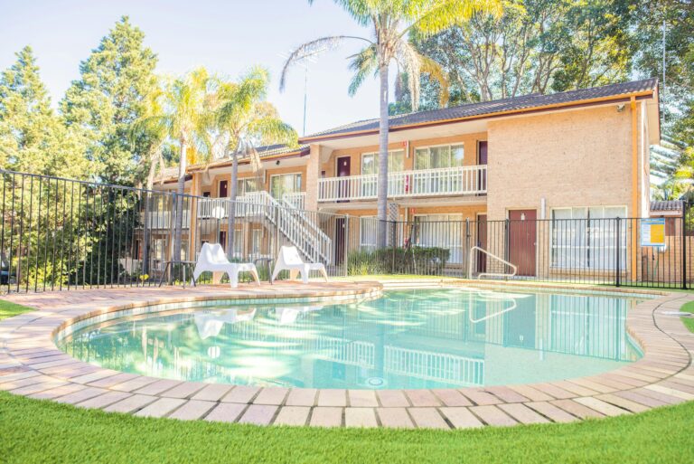 Outdoor swimming pool at Sutherland Motel, two-story blonde brick motel
